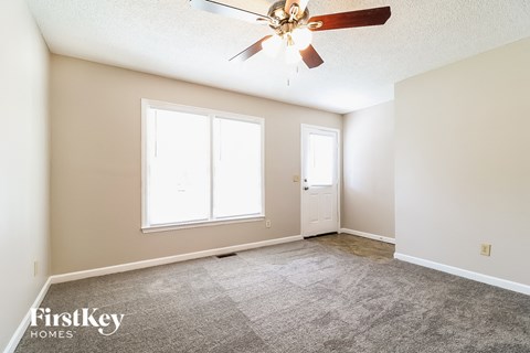 a living room with carpet and a ceiling fan