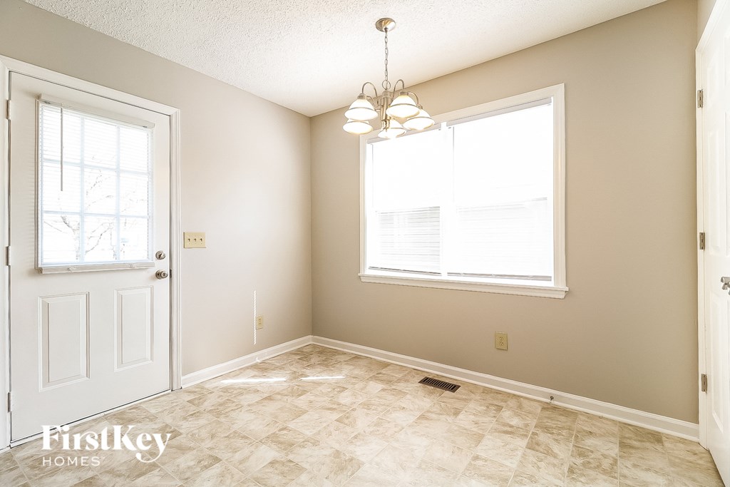 an empty dining room with a white door and a window