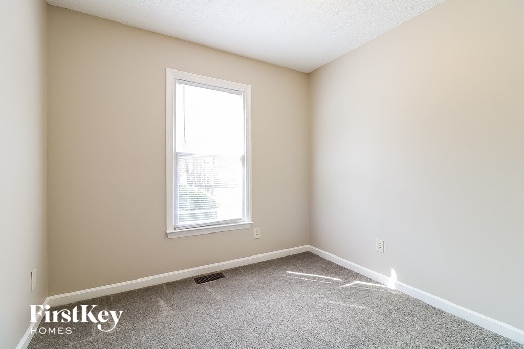 a bedroom with a window and a carpeted floor