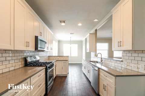 a kitchen with white cabinets and a stove and a sink