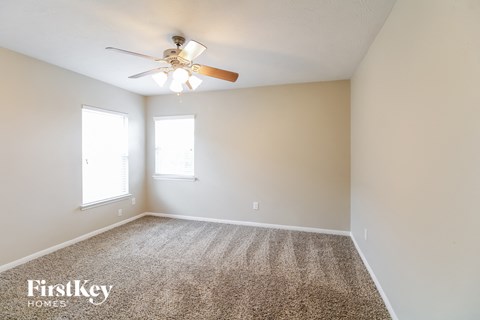 the spacious living room with ceiling fan and carpet