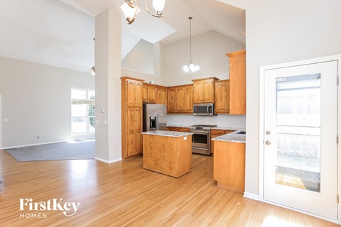 a kitchen with wooden cabinets and a door to the living room