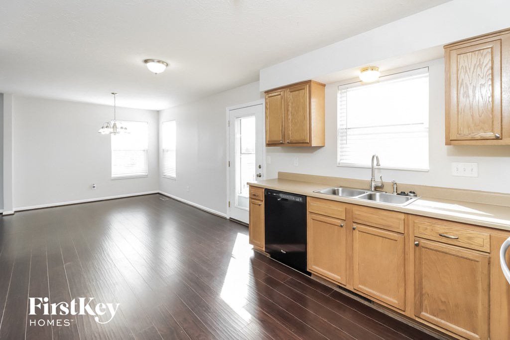 a kitchen and living room with wood floors and wooden cabinets