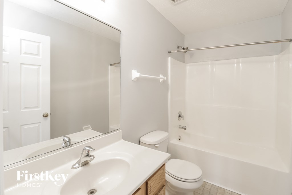 a white bathroom with a large mirror and a white toilet and sink