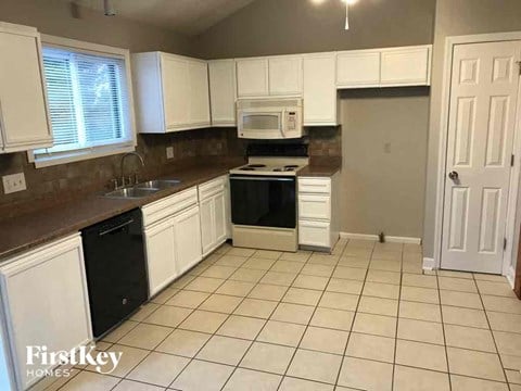 a kitchen with white cabinets and a sink and a stove