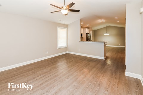 A spacious room with wooden flooring and a ceiling fan.