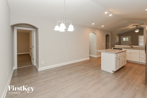 A spacious kitchen with a dining area and a hallway leading to a doorway.