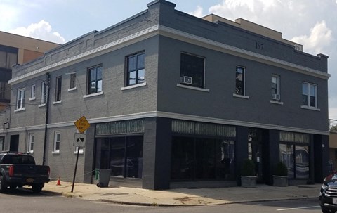 A grey building with a yellow sign in front of it.