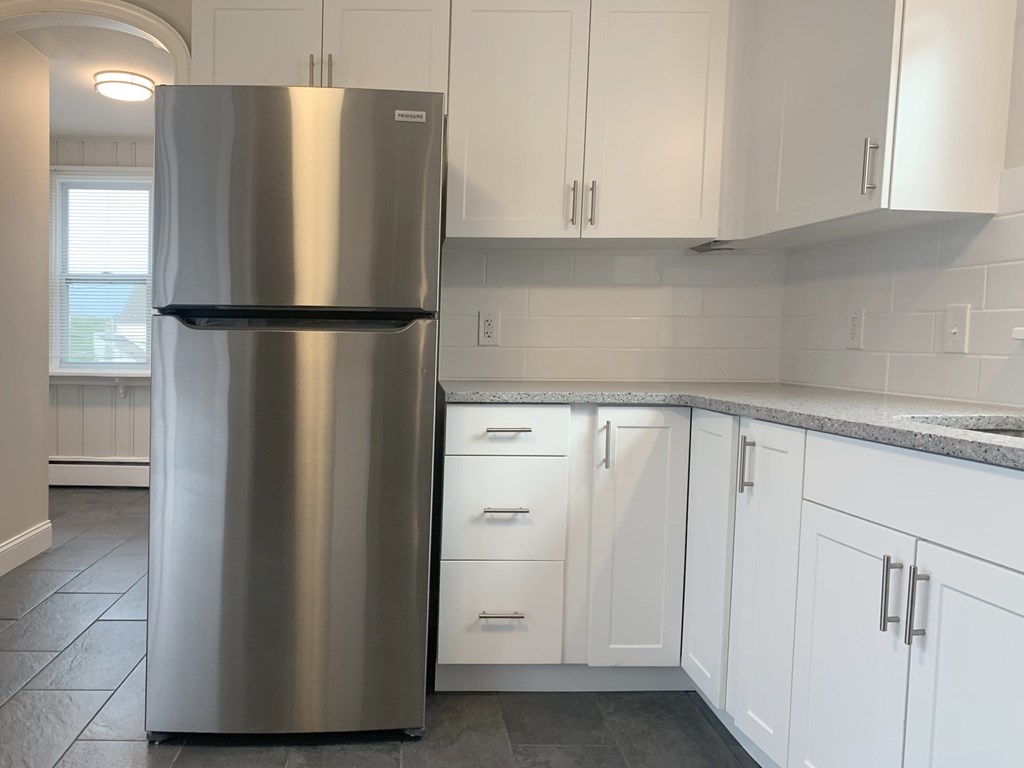 a kitchen with white cabinets and a stainless steel refrigerator