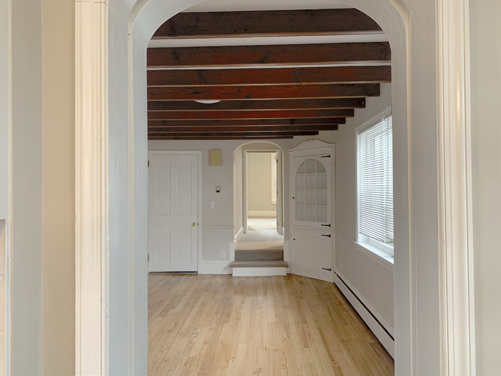 a view of a hallway with wood floors and white walls