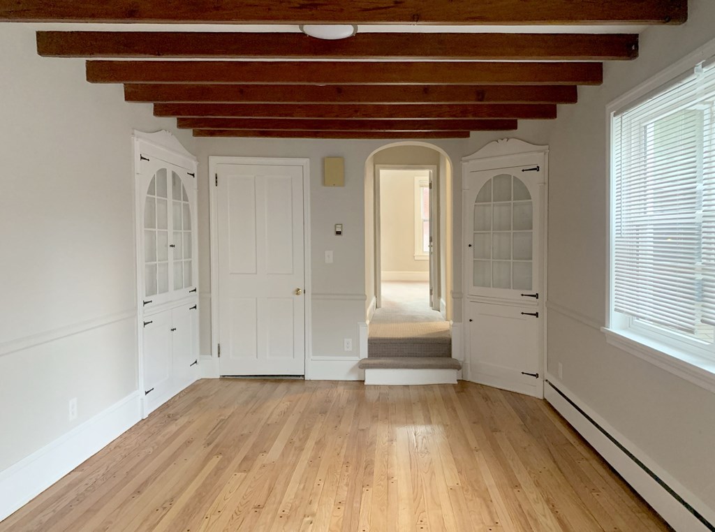 a living room with white walls and wooden floors and white doors