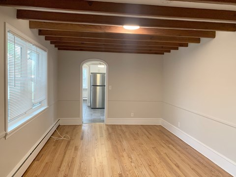 an empty living room with wooden floors and a large window