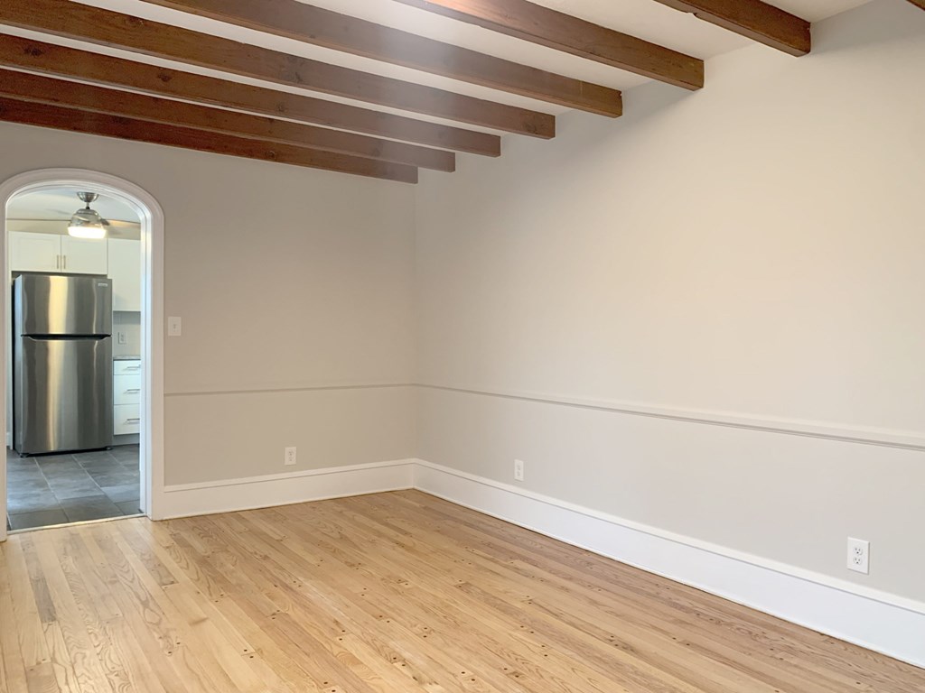 an empty living room with white walls and a wooden floor