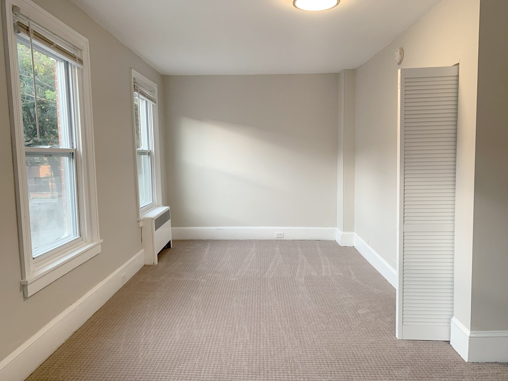 an empty living room with two windows and a carpet