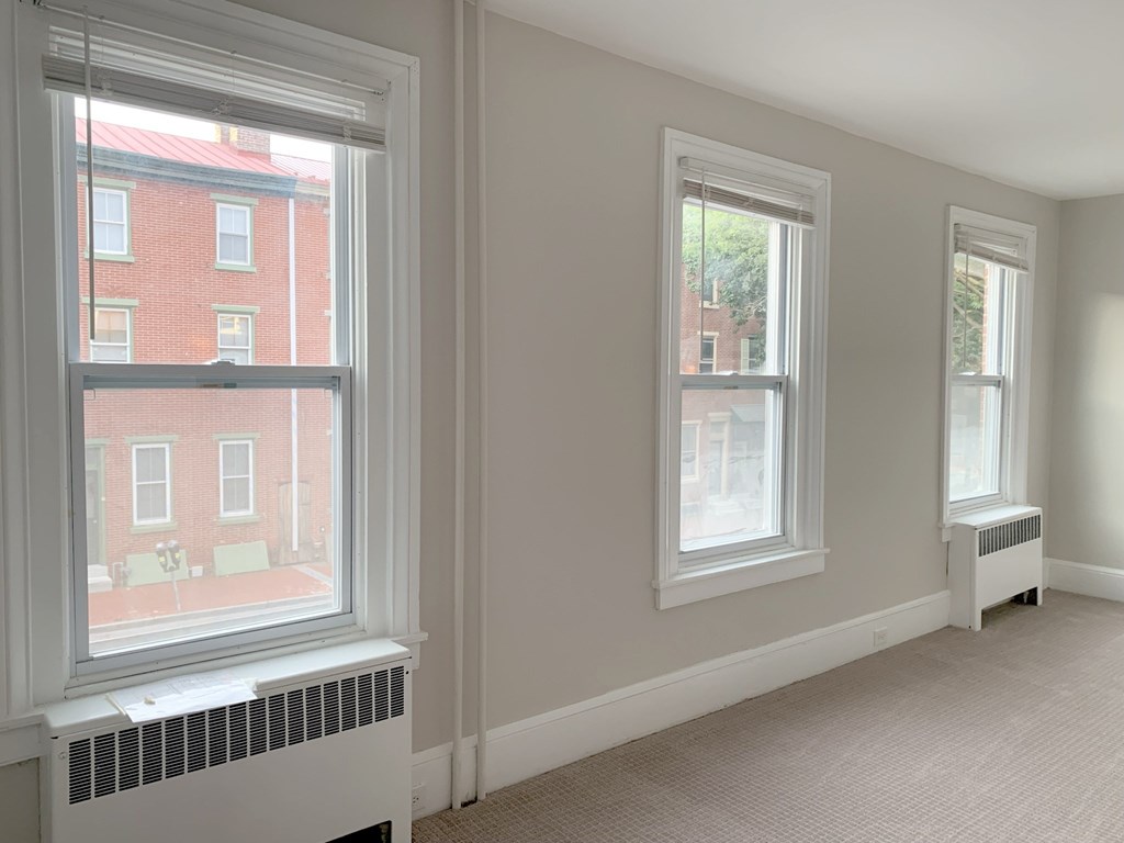 a bedroom with two windows and a radiator on the floor