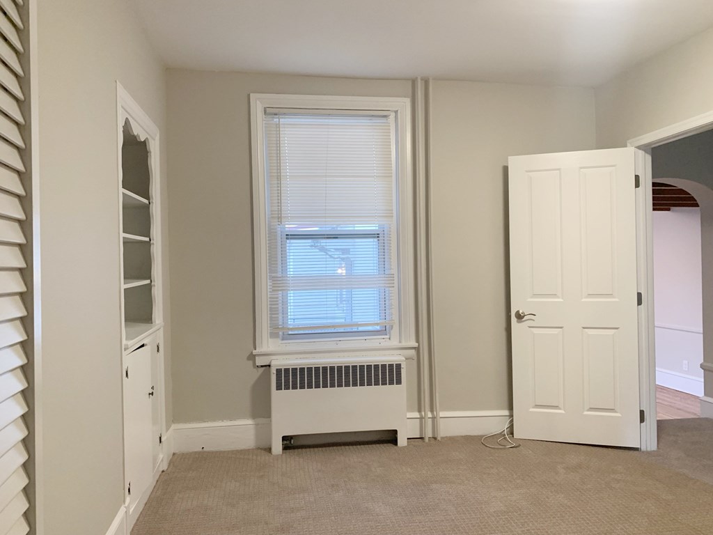 a small room with a window and a radiator and a white door