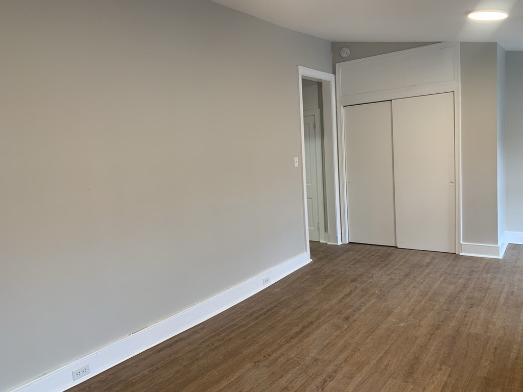 an empty living room with white walls and a wood floor