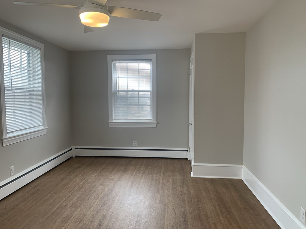 an empty living room with wood floors and a ceiling fan