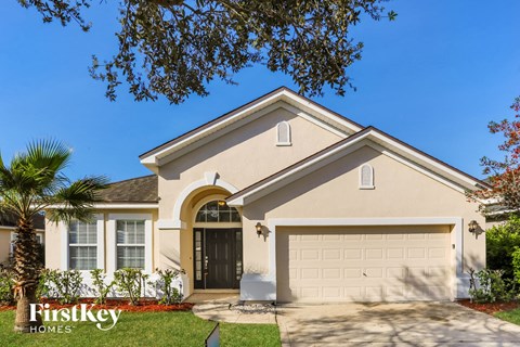 A house with a garage door and a palm tree in front.