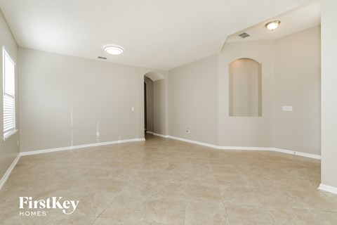 A spacious empty room with a tiled floor and a doorway leading to another room.