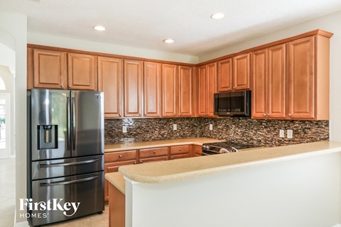 A kitchen with wooden cabinets and a black fridge.