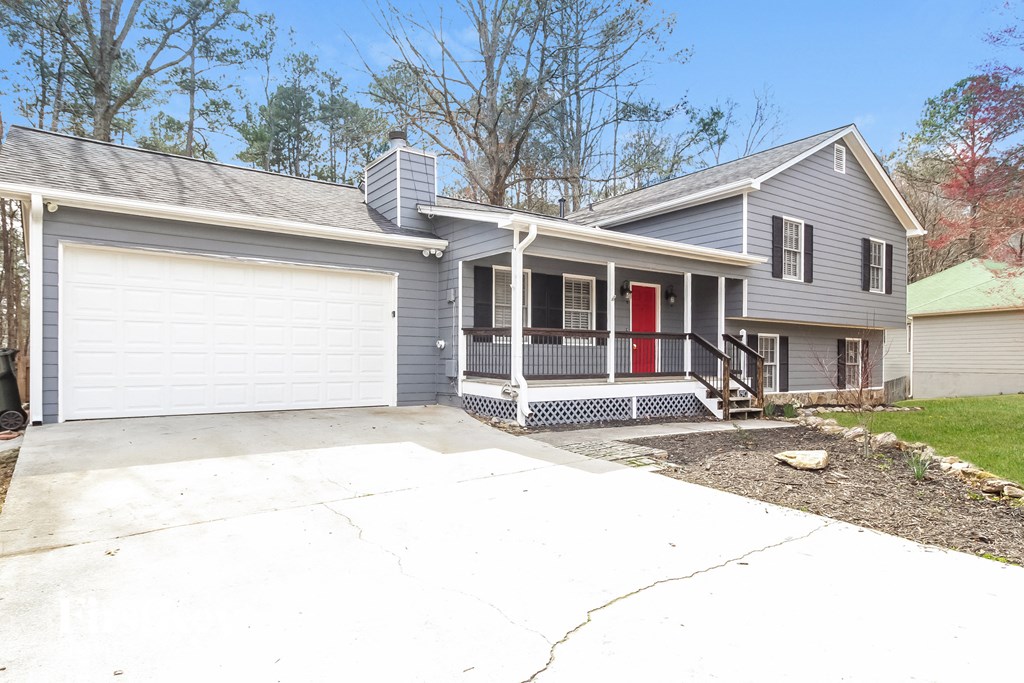 a gray house with a red door and a driveway