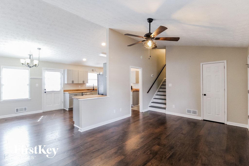 an empty living room and kitchen with a ceiling fan