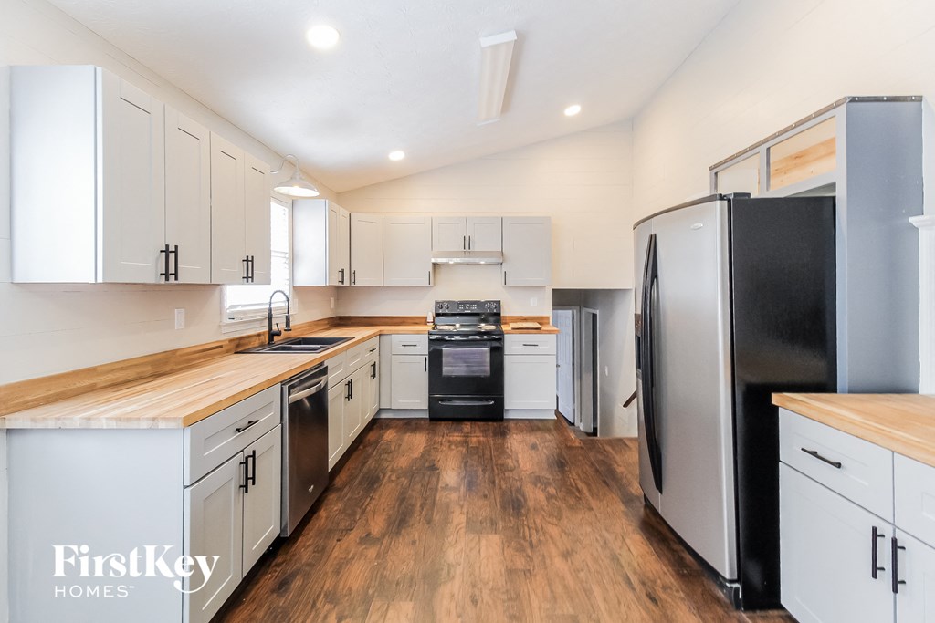 a kitchen with white cabinets and a black stove and refrigerator