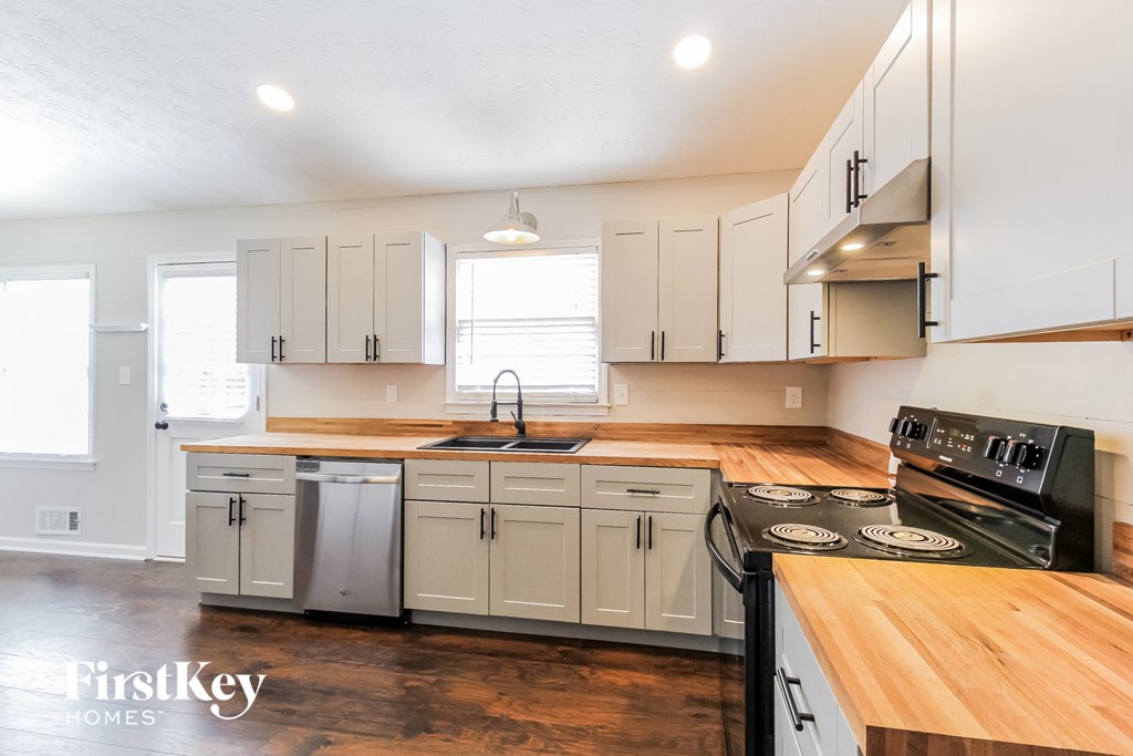 a kitchen with white cabinets and wooden counter tops and a stove top oven