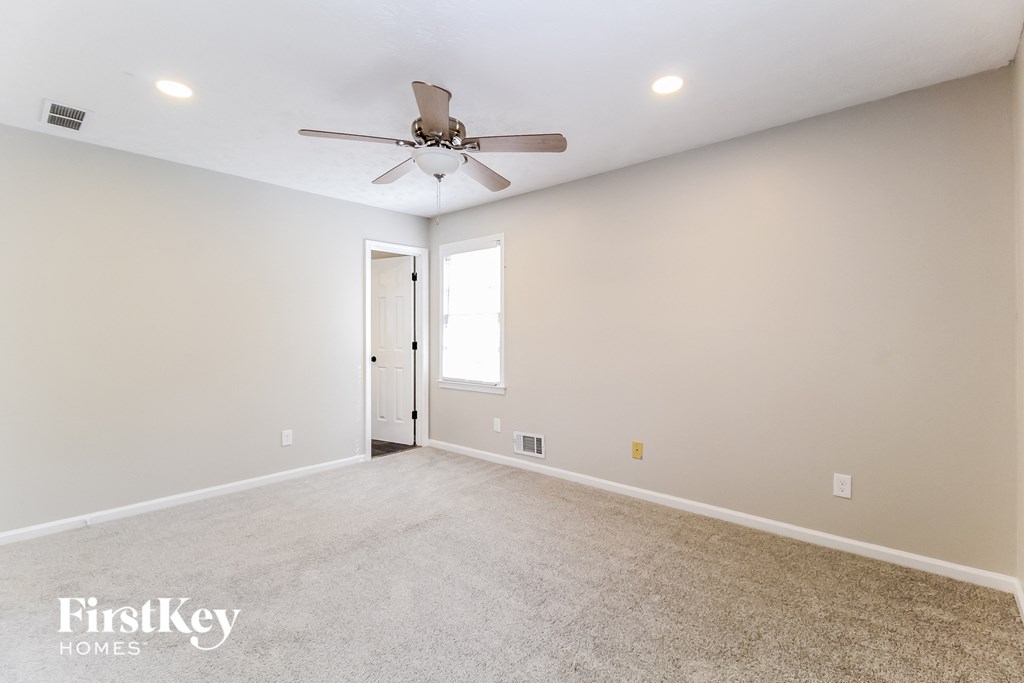 the spacious living room with ceiling fan and carpeting
