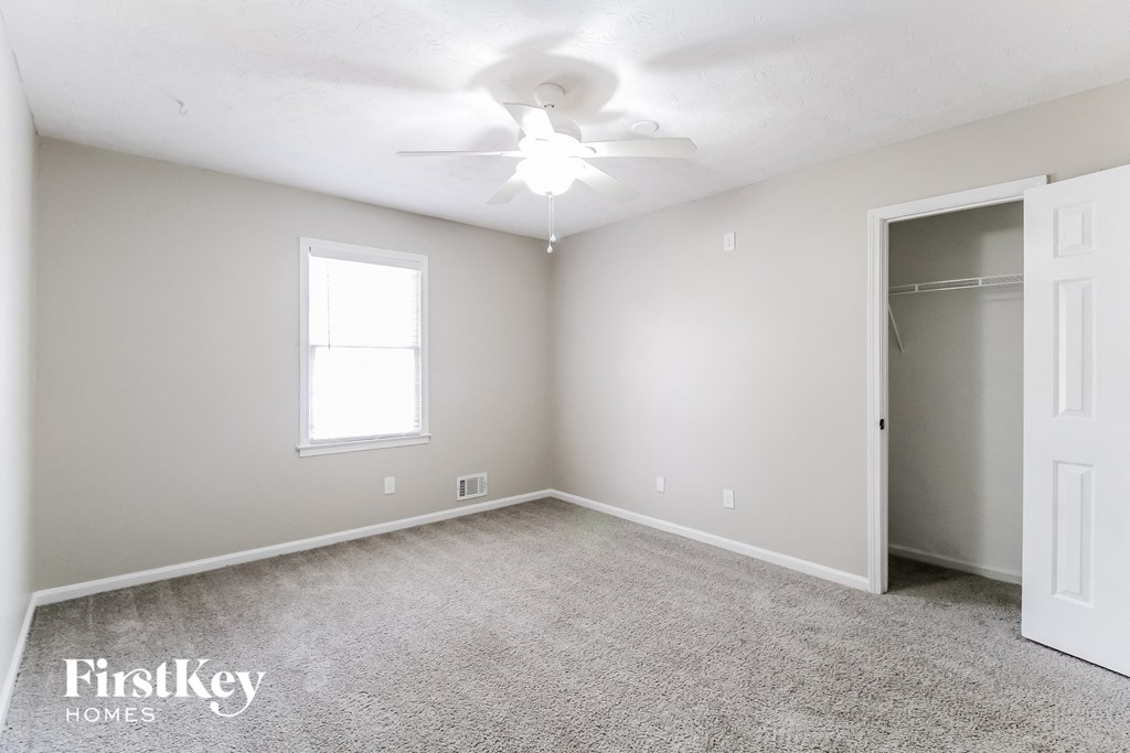 a bedroom with carpet and a ceiling fan and a closet