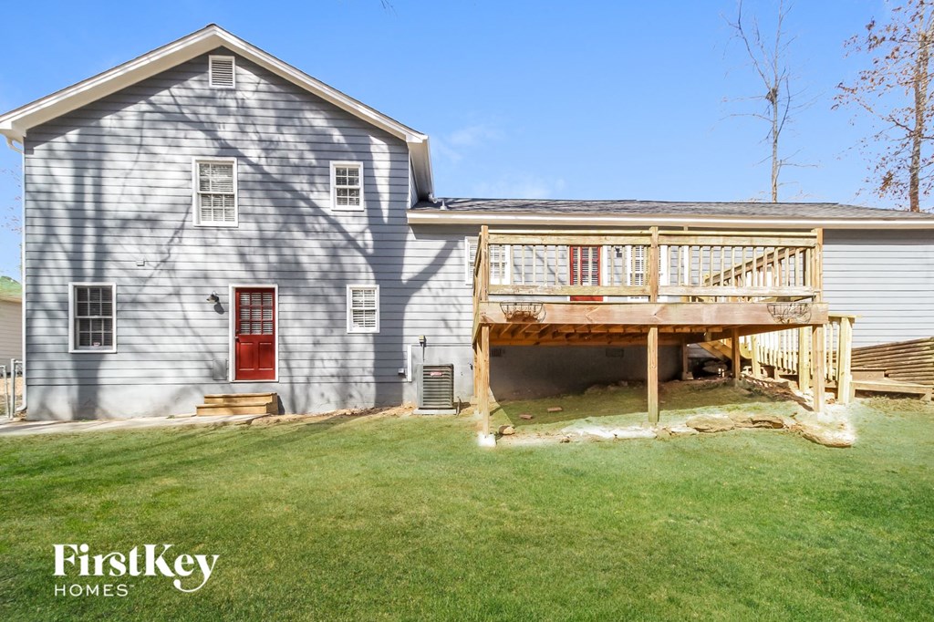 the back of a white house with a deck and a porch