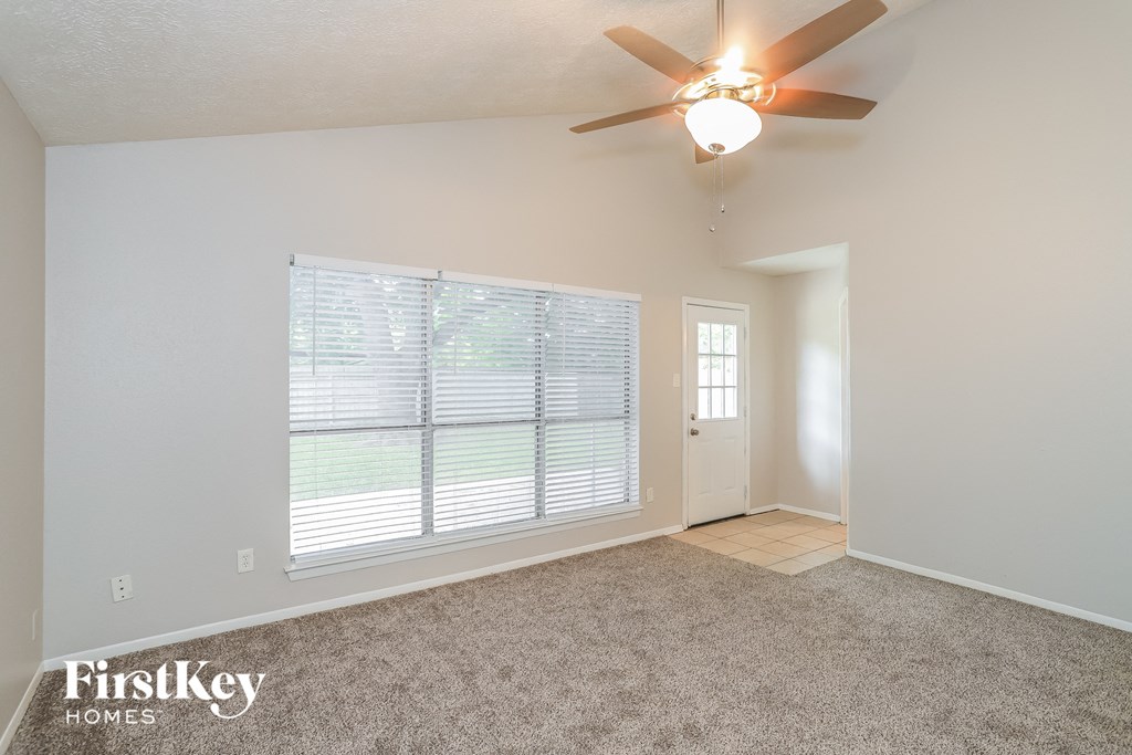 A room with a ceiling fan and a window with blinds.