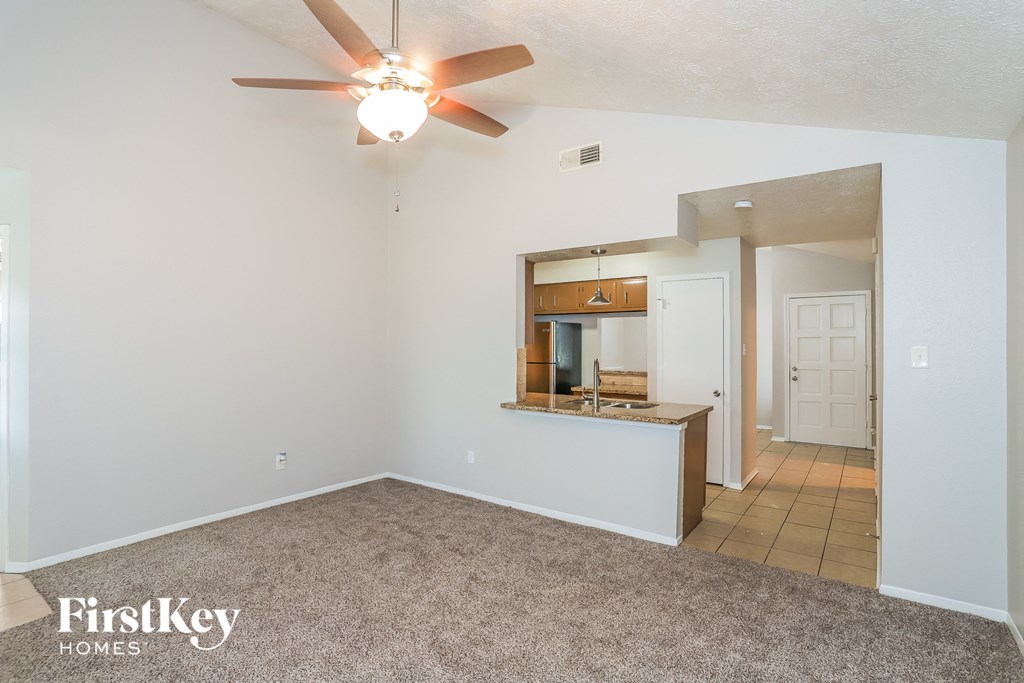 A spacious living room with a ceiling fan and a mirror on the wall.