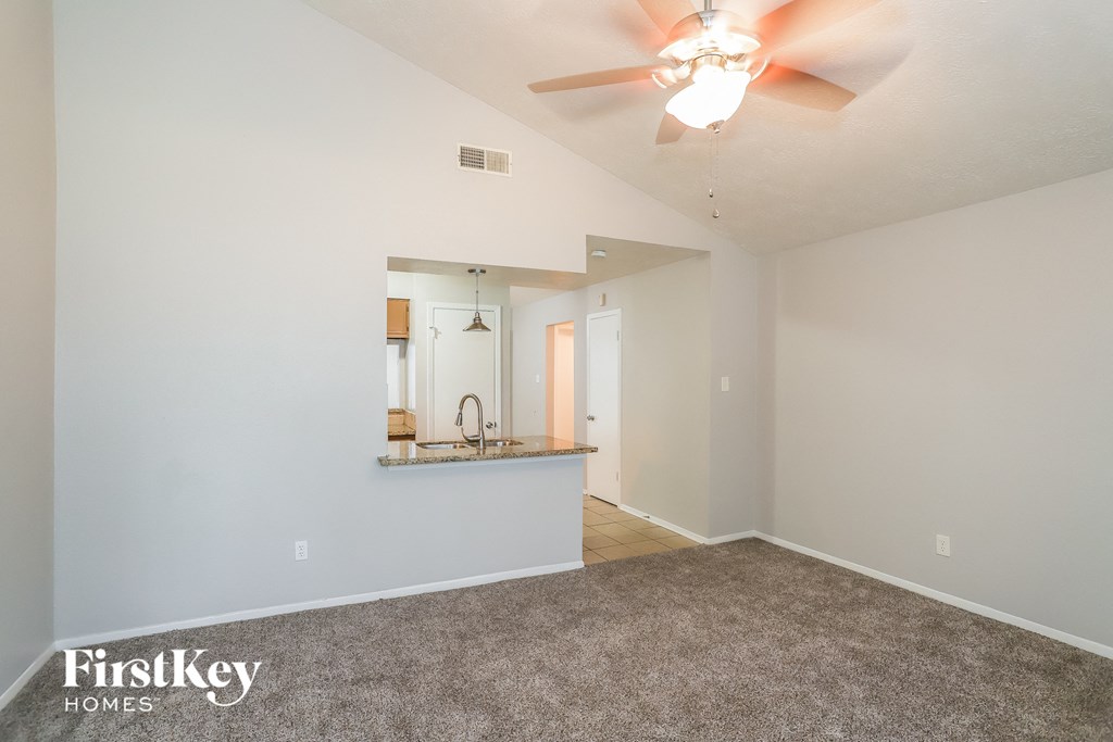 A spacious room with a carpeted floor and a ceiling fan.