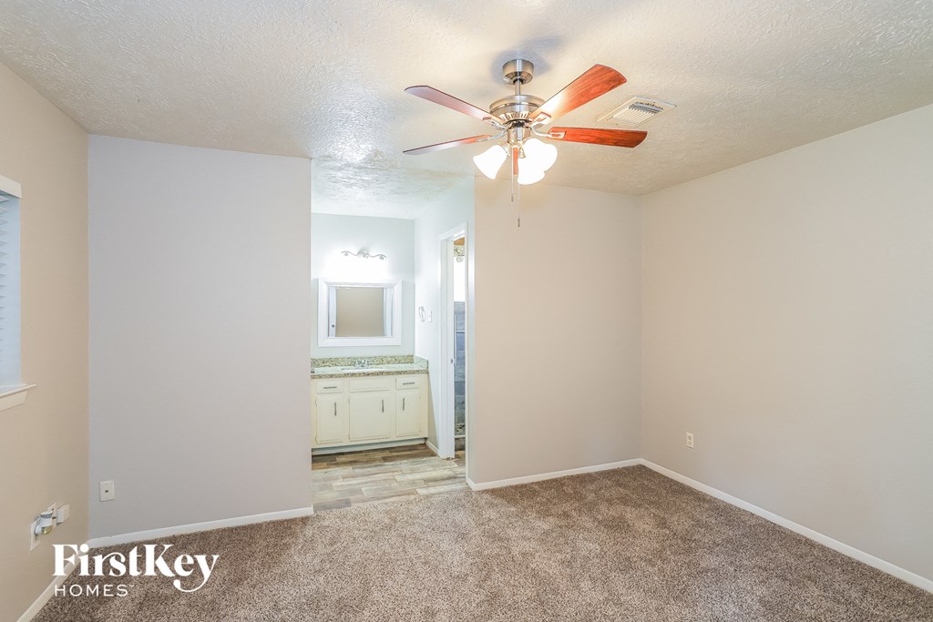 A bedroom with a carpeted floor and a ceiling fan.