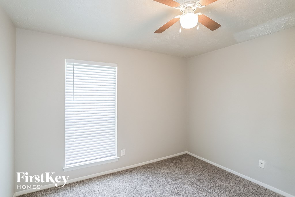 A room with a ceiling fan and a window with blinds.
