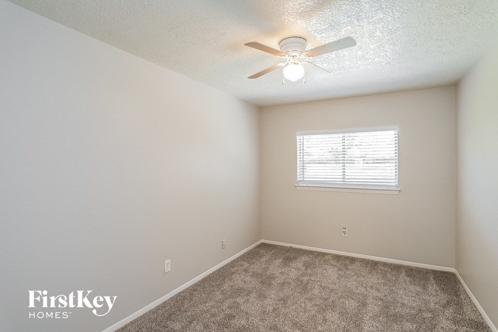 A room with a ceiling fan and a window with blinds.