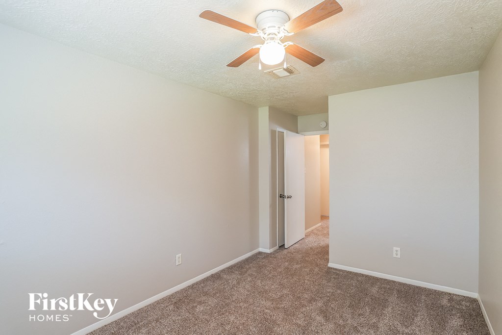 A room with a ceiling fan and carpeted floor.