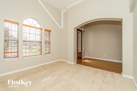 an empty living room with a large arched door and windows