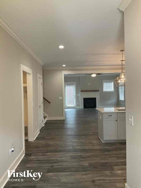 A spacious kitchen and living room with wood flooring and white walls.