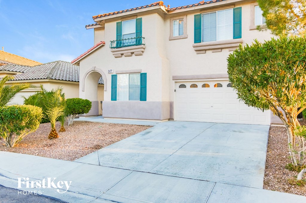 A house with a driveway and a tree in front.