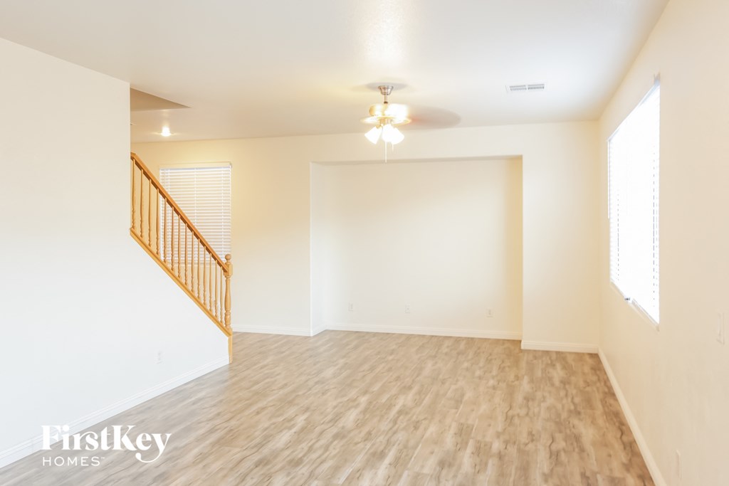 A spacious room with wooden flooring and a staircase with a wooden railing.