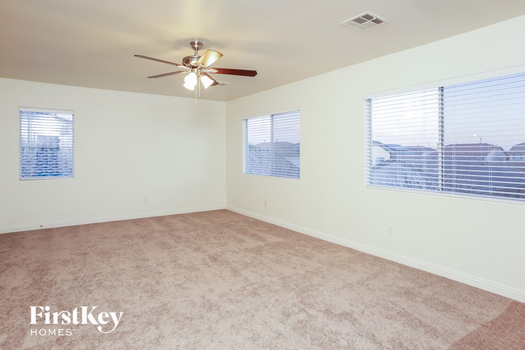 A room with a ceiling fan and two windows with blinds.