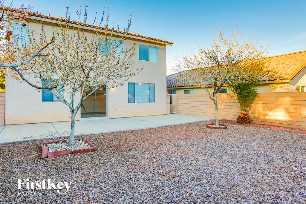 A house with a gravel driveway and two trees in front of it.