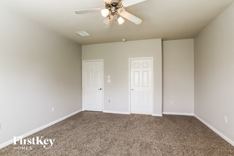 the master bedroom has carpet and a ceiling fan