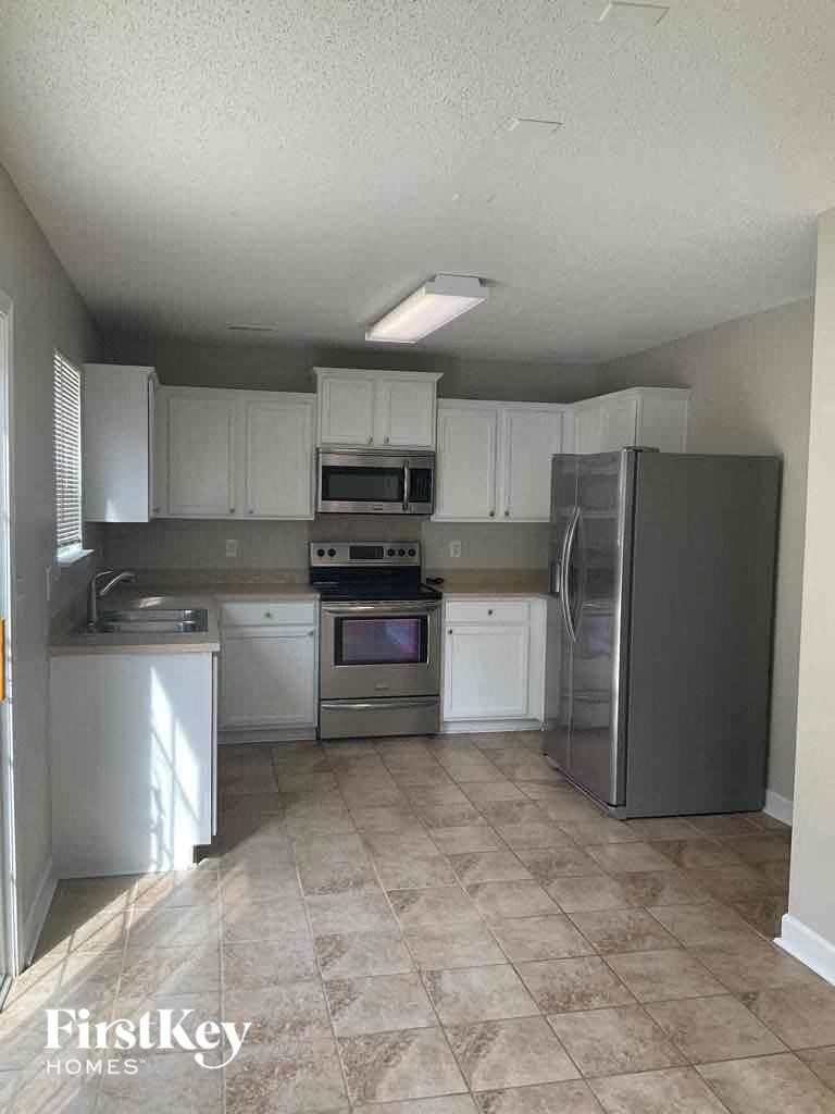 an empty kitchen with stainless steel appliances and white cabinets