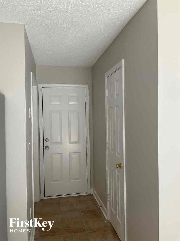 an empty hallway with a white door and a closet