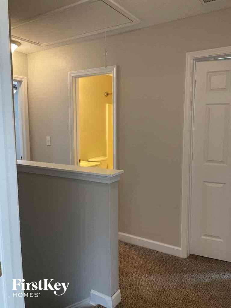 a small hallway with a mirror and a door to a bathroom