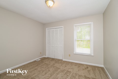 a bedroom with carpet and two windows